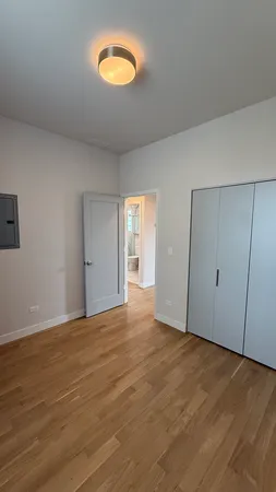 a view of an empty room with wooden floor and window