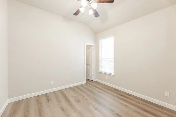 an empty room with fireplace and a kitchen space with a sink