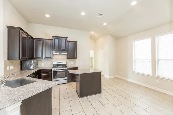 a kitchen with stainless steel appliances granite countertop a sink stove and cabinets