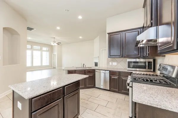 a kitchen with stainless steel appliances granite countertop a sink stove and refrigerator