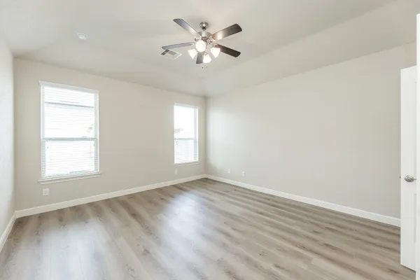 an empty room with wooden floor and windows