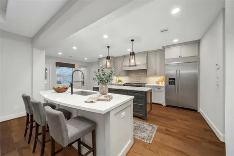a kitchen with a sink a stove a refrigerator and white cabinets with wooden floor