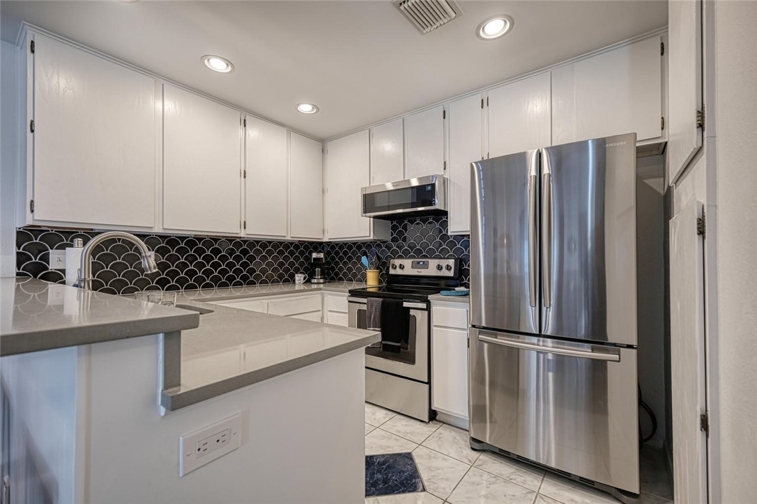 1748 Ohlen Road, Unit 74 Austin, TX 78757 - Photo 6 of 15 a kitchen with a refrigerator a sink and white cabinets