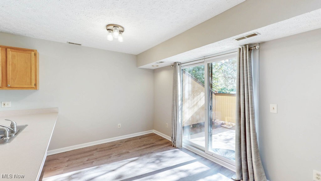 1426 Loop Road, Unit 1426 Kent, OH 44240 - Photo 11 of 40 Dining area featuring a textured ceiling and light wood-style floors, updated lighting and sliding doors leading to private patio area.