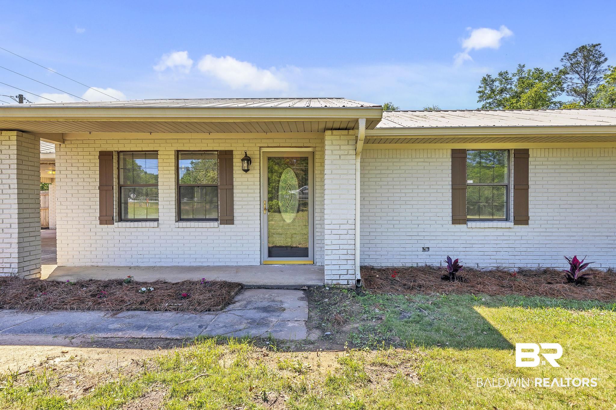 11964 Stroh Road Daphne, AL 36527 - Photo 10 of 58 Doorway to property with brick siding, a porch, and metal roof