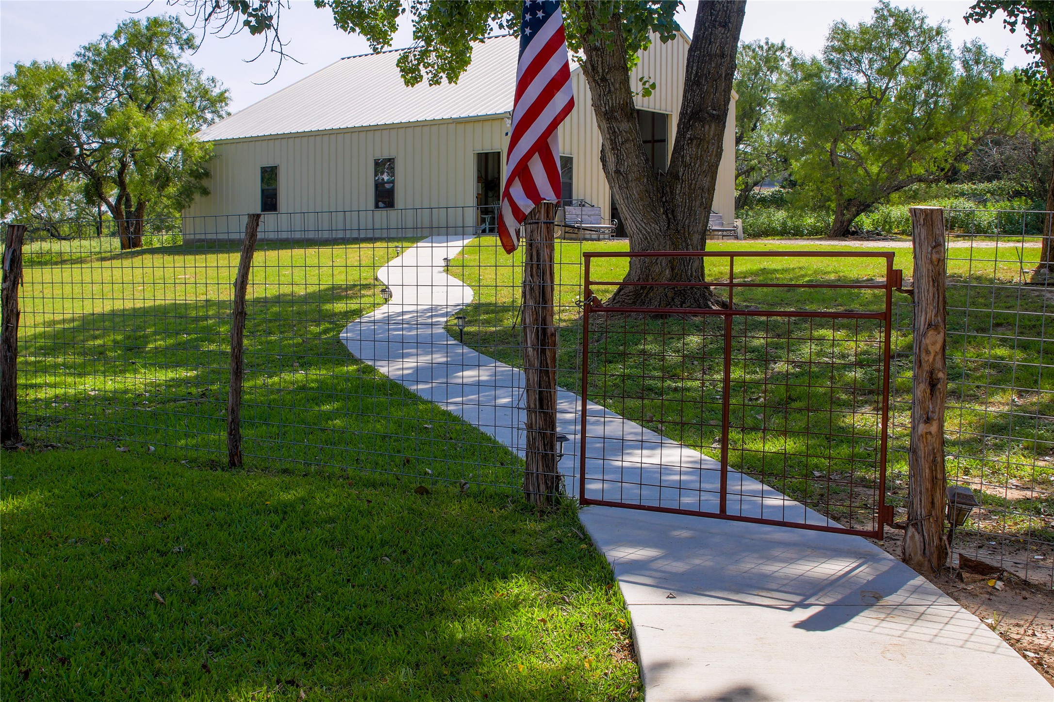 405 Frederick Road Fredericksburg, TX 78624 - Photo 19 of 29 A winding concrete pathway leads to the metal building.