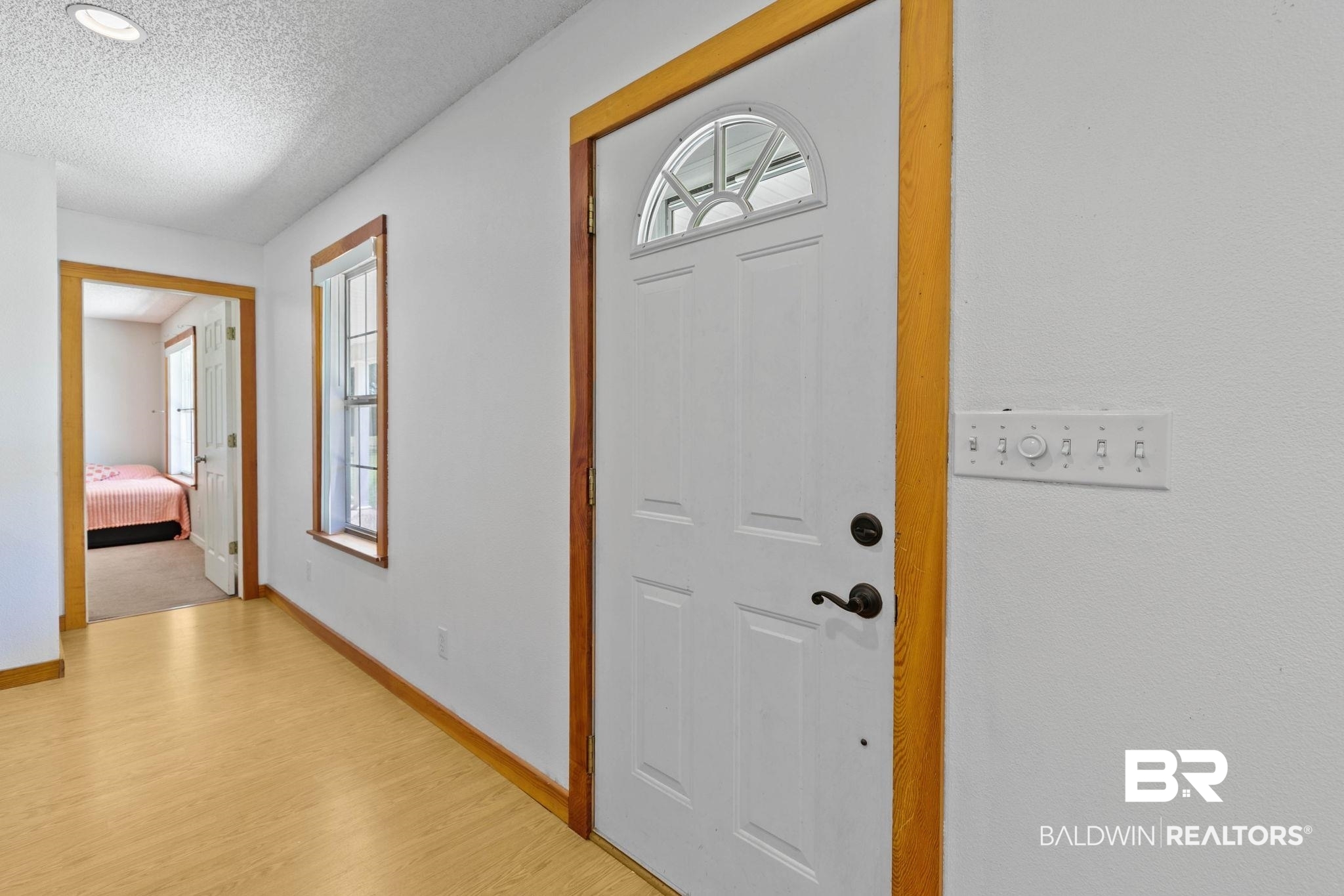 20219 Greek Cemetery Road Robertsdale, AL 36567 - Photo 13 of 41 Entryway featuring a white paneled door with an arched transom window, wood-finish flooring, and natural wood trim