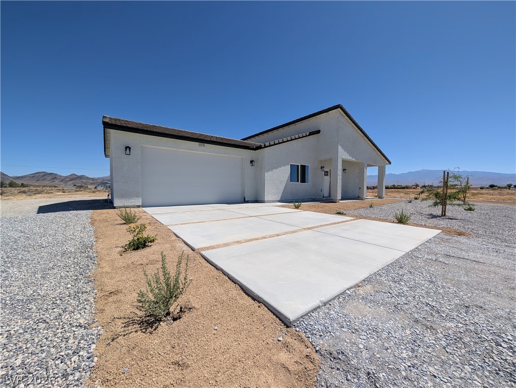 4670 Medicine Man Road Pahrump, NV 89048 - Photo 2 of 36 A newly constructed residence boasting a prominent attached garage and expansive concrete driveway.