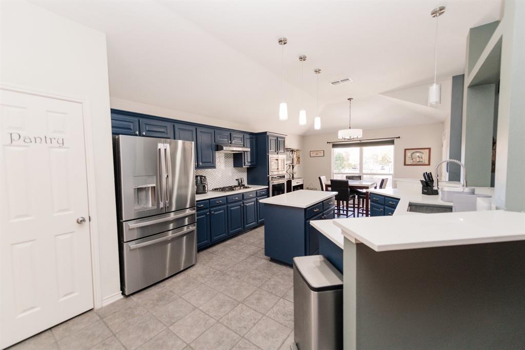 2107 Lacebark Lane Rockwall, TX 75087 - Photo 6 of 34 a kitchen with stainless steel appliances kitchen island granite countertop a refrigerator and a sink
