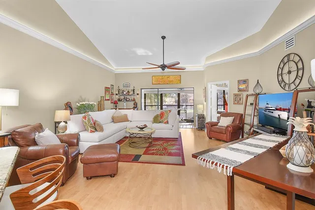 a living room with furniture a clock and a ceiling fan