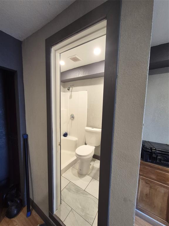 815 Bonnie View Road Dallas, TX 75203 - Photo 26 of 29 Bathroom featuring a shower stall, a textured ceiling, and a textured wall