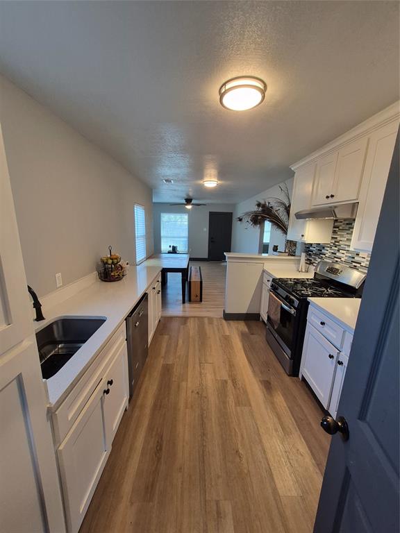 815 Bonnie View Road Dallas, TX 75203 - Photo 29 of 29 Kitchen with a peninsula, white cabinets, appliances with stainless steel finishes, a textured ceiling, and open floor plan