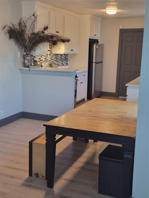 815 Bonnie View Road Dallas, TX 75203 - Photo 8 of 29 Kitchen featuring white cabinetry, backsplash, freestanding refrigerator, and light wood-style floors