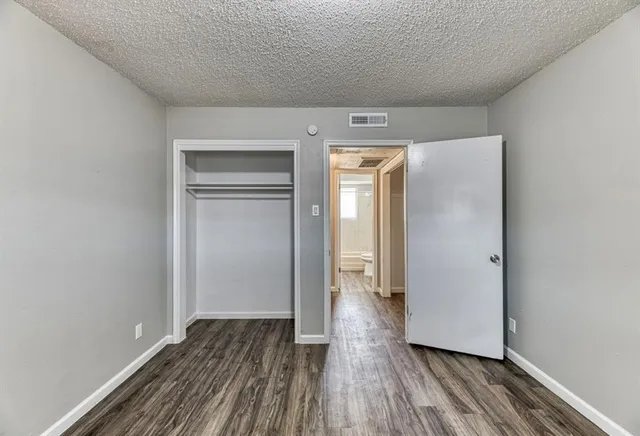 a view of an empty room with wooden floor and closet
