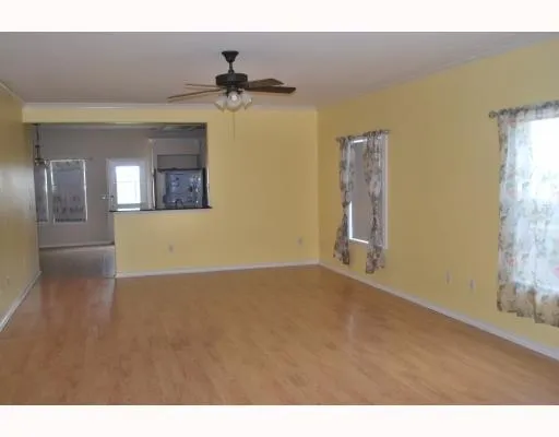 a view of a big room with wooden floor and chandelier fan