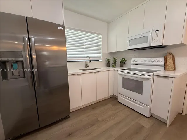 a kitchen with white cabinets and white appliances