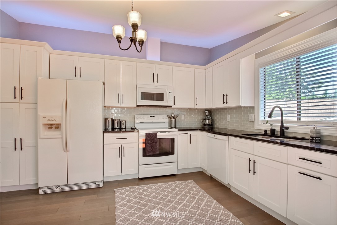 21928 8th Place West Bothell, WA 98021 - Photo 8 of 31 a kitchen with granite countertop white cabinets white appliances a sink and a window