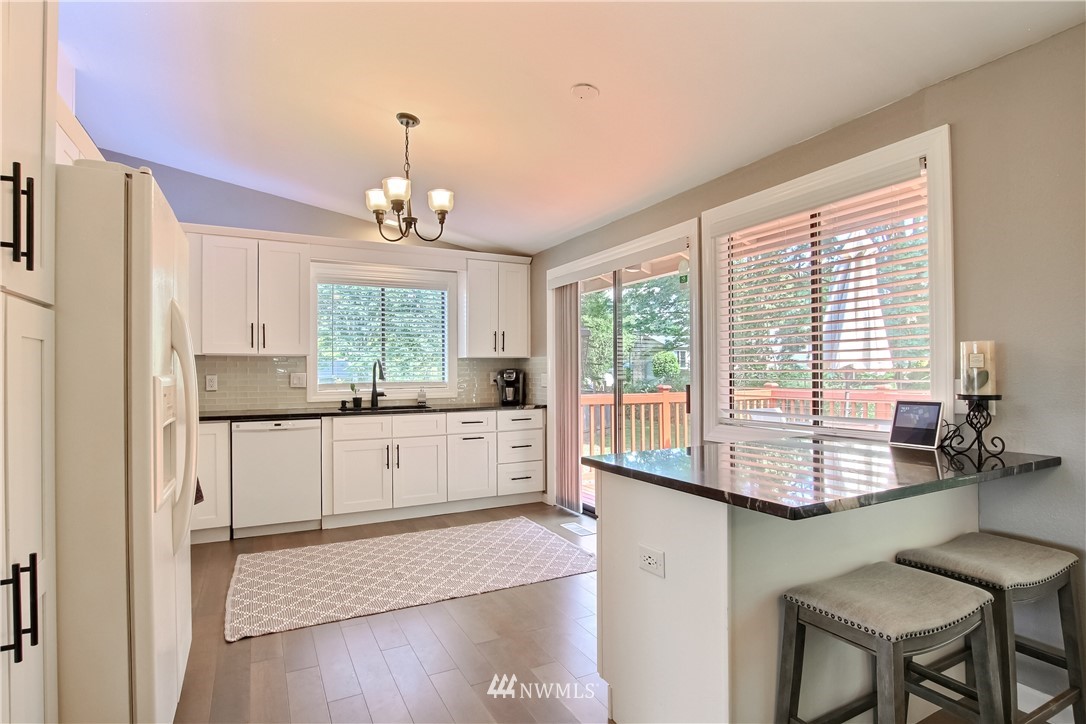 21928 8th Place West Bothell, WA 98021 - Photo 10 of 31 a kitchen with kitchen island granite countertop a stove a refrigerator and a dining table with wooden floor