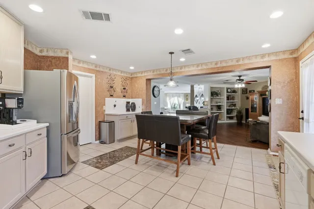 a kitchen with stainless steel appliances kitchen island granite countertop dining table chair and a refrigerator