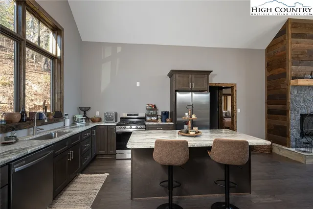 a kitchen with a sink a stove and chairs with wooden floor