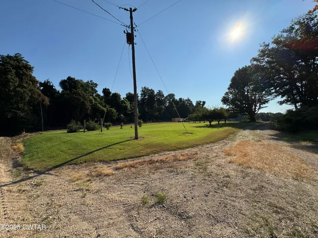 a view of a house with a small yard and a large tree