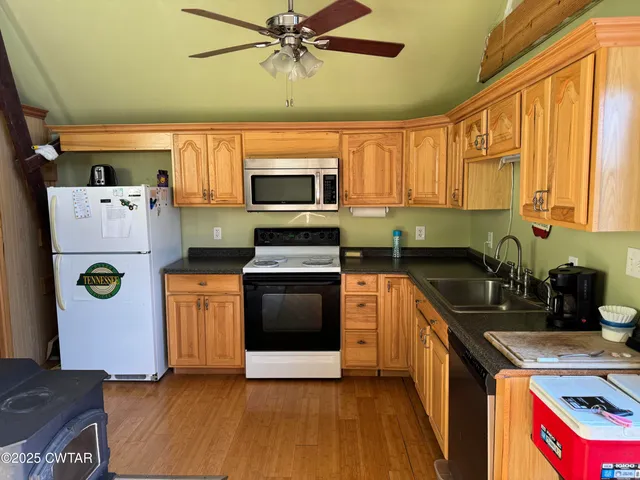 a kitchen with stainless steel appliances kitchen island granite countertop a refrigerator a sink a stove and white cabinets