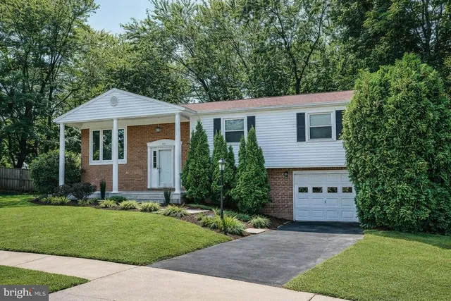 a front view of a house with a garden and trees