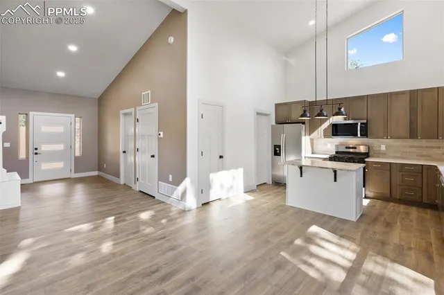a kitchen with stainless steel appliances kitchen island granite countertop a sink cabinets and wooden floor