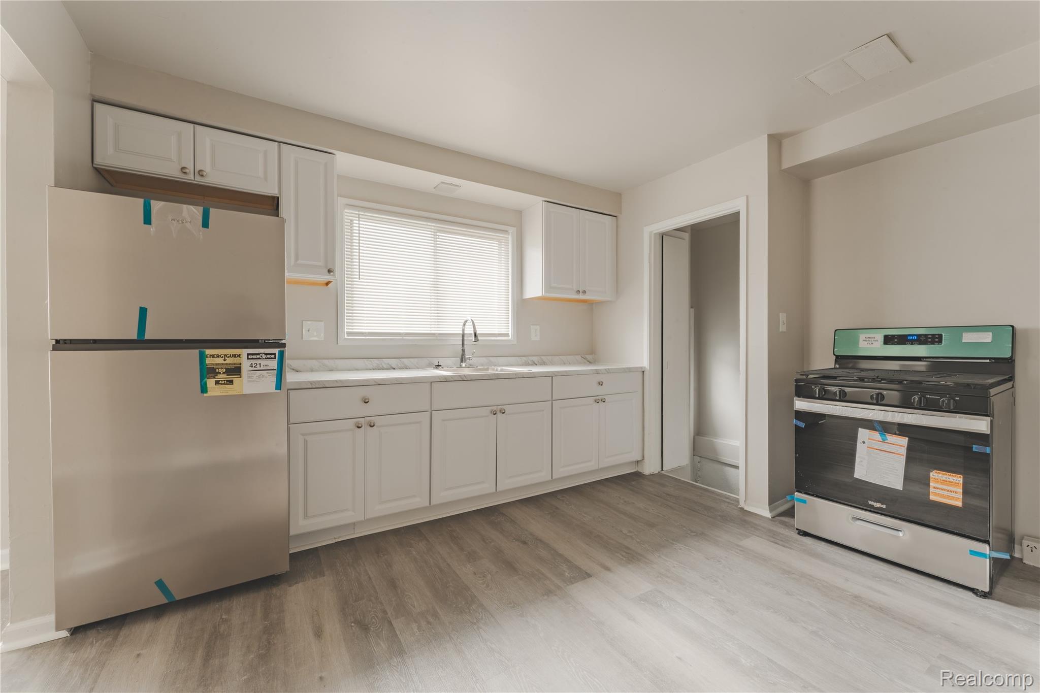 93 West Princeton Avenue Pontiac, MI 48340 - Photo 20 of 31 Modern kitchen featuring white shaker cabinetry, stainless steel appliances, marble-look countertops, a stainless steel sink, and wood-finish flooring