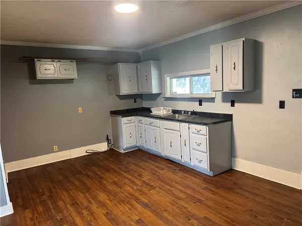 a kitchen with granite countertop a sink cabinets and wooden floor