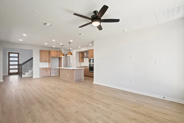 a view of an empty room with wooden floor and a ceiling fan