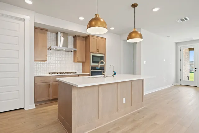 a kitchen with kitchen island granite countertop a sink a stove and a chandelier