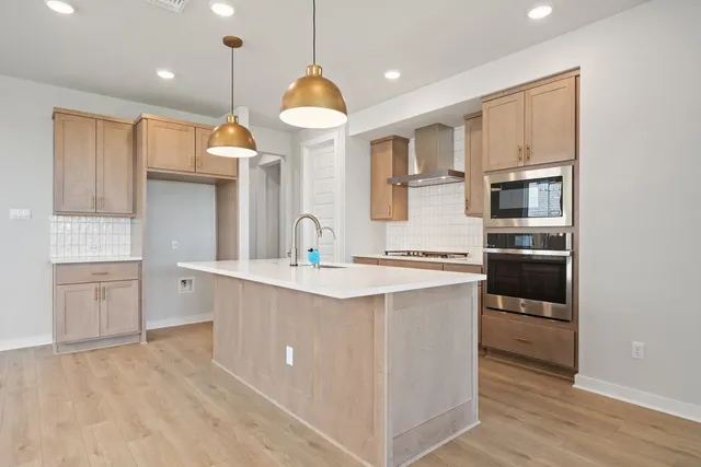 a kitchen with kitchen island a counter top space a sink stainless steel appliances and cabinets