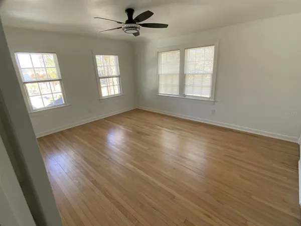 a view of an empty room with wooden floor and a window