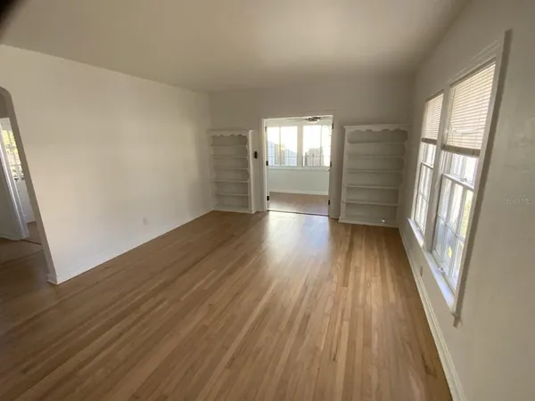 an empty room with wooden floor and windows