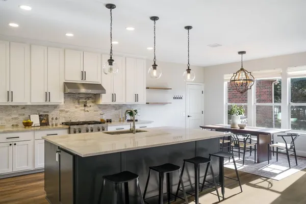 a kitchen with stainless steel appliances granite countertop a sink a stove and a wooden floor