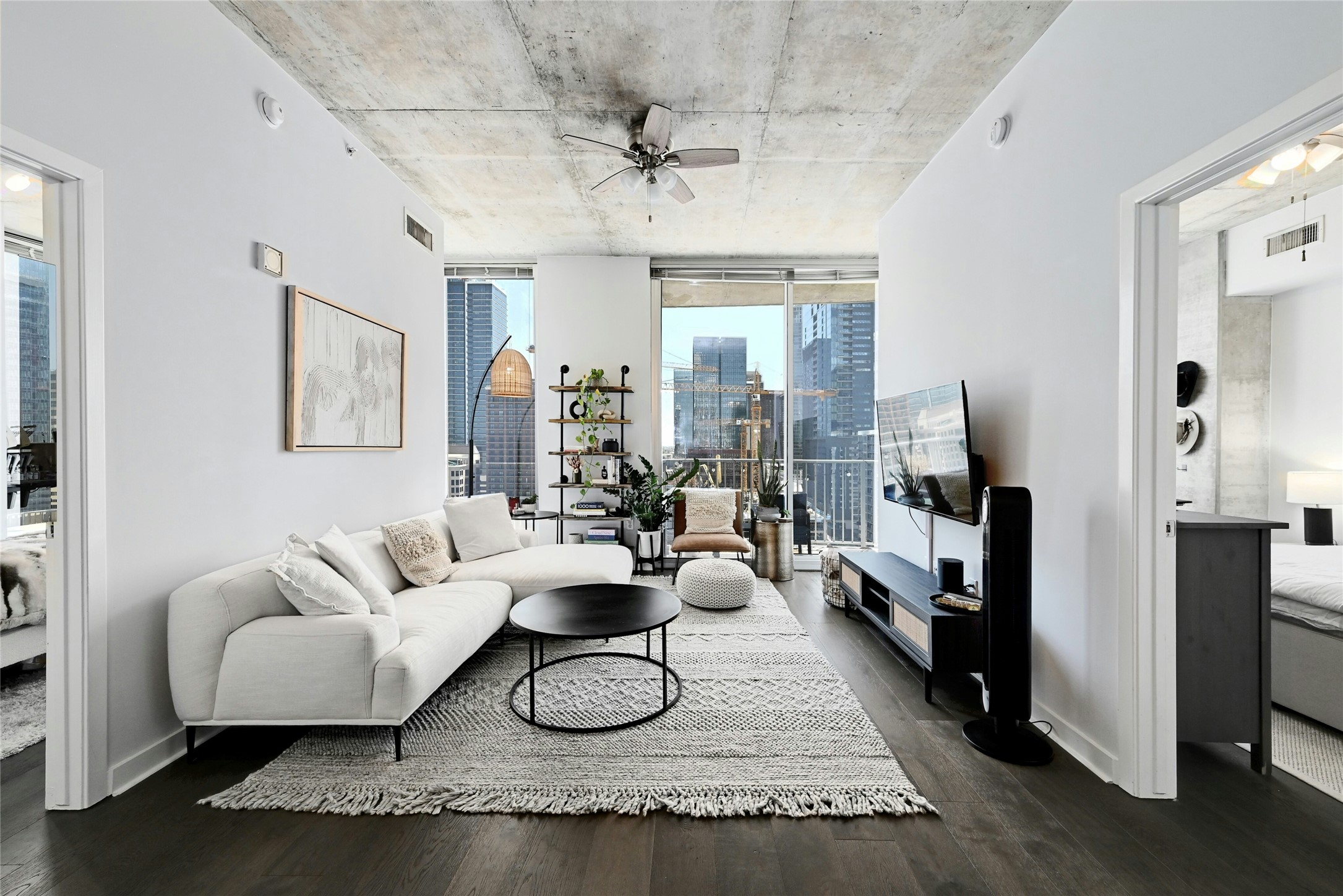 Living room featuring dark wood-style flooring, a ceiling fan, and floor to ceiling windows