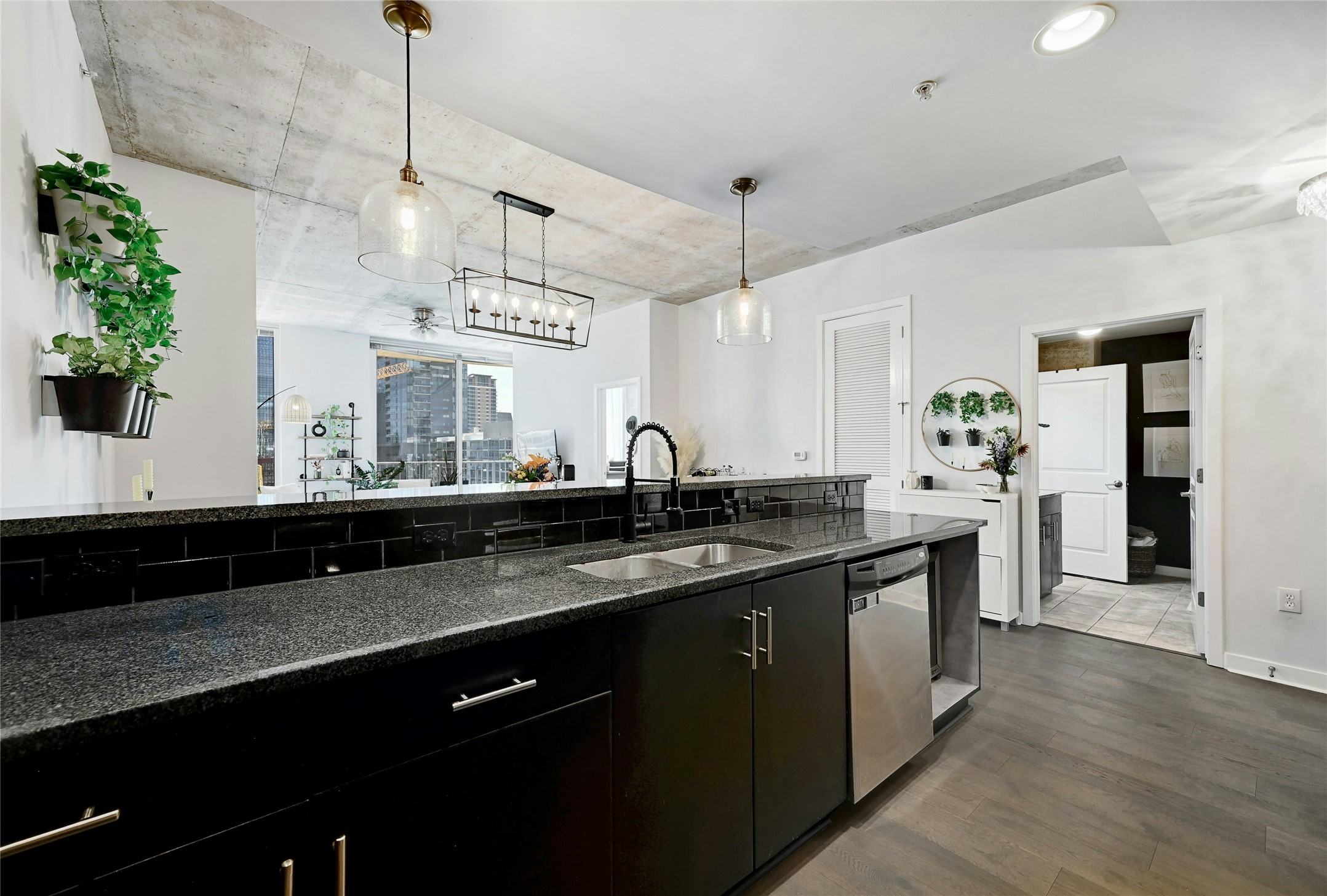 360 Nueces Street, Unit 1809 Austin, TX 78701 - Photo 9 of 25 Kitchen with dark stone counters, dark cabinets, dark wood-type flooring, decorative light fixtures, and dishwasher