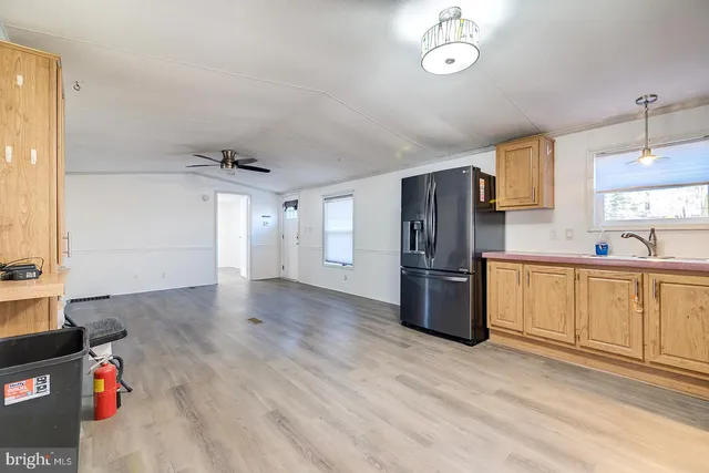 a kitchen with stainless steel appliances granite countertop a refrigerator a sink dishwasher a stove and white countertops with wooden floor