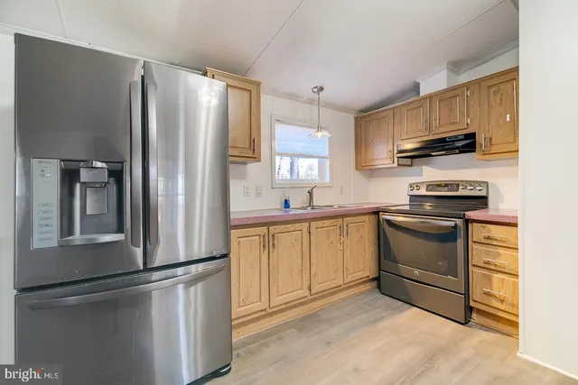 a kitchen with stainless steel appliances granite countertop a refrigerator sink and stove