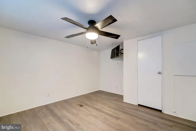 an empty room with wooden floor and ceiling fan