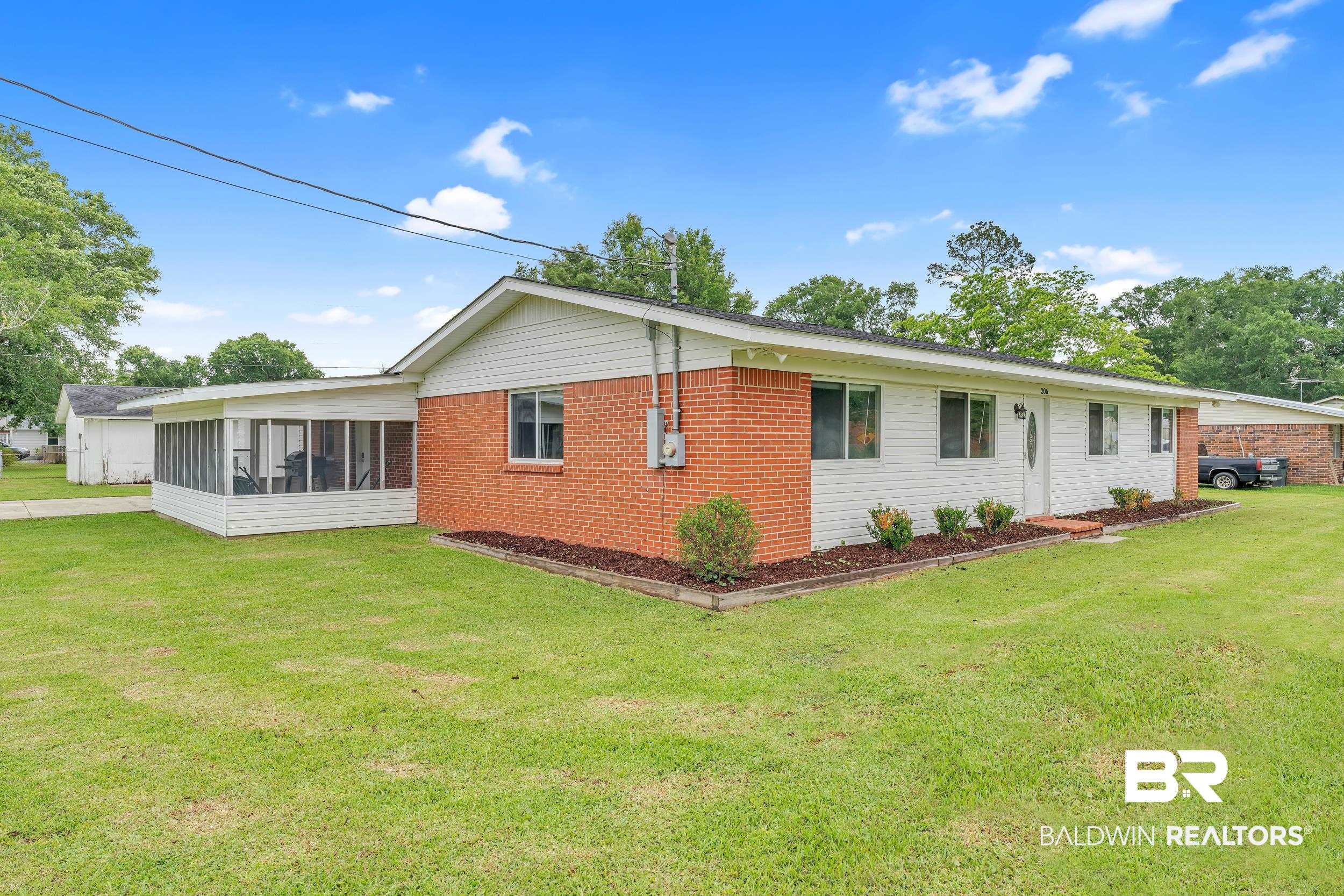 206 West Jackson Avenue Summerdale, AL 36580 - Photo 6 of 37 Rear view of house featuring a sunroom, brick siding, and a lawn