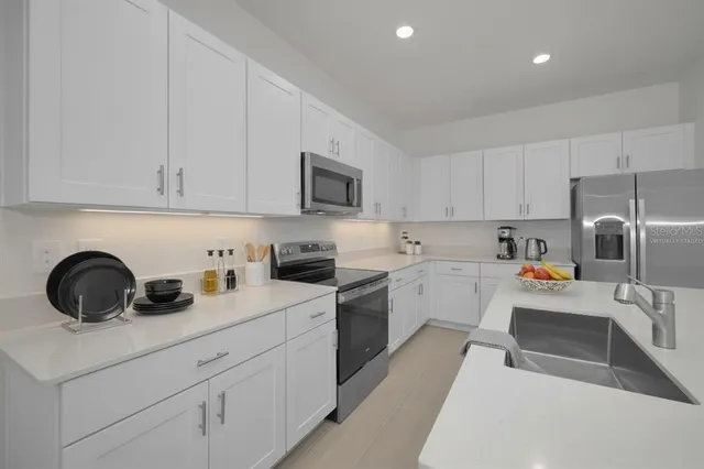 a kitchen with granite countertop white cabinets and stainless steel appliances