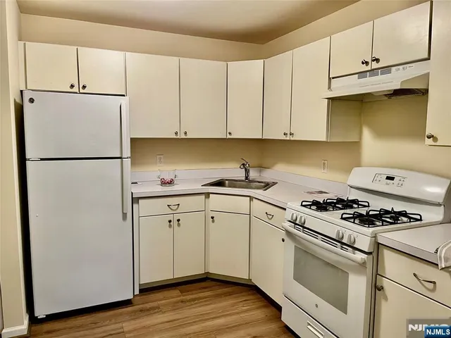 a kitchen with cabinets appliances and wooden floor