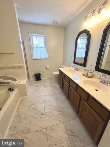 a spacious bathroom with a double vanity sink a mirror and a bathtub