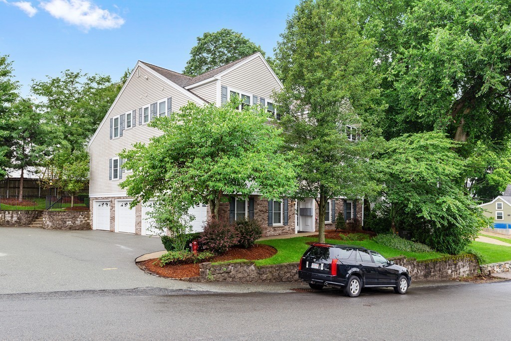 24 Wall Street, Unit E Canton, MA 02021 - Photo 2 of 19 a car parked in front of a house with a small yard and large trees