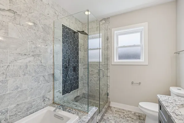 a bathroom with a granite countertop sink a toilet and shower