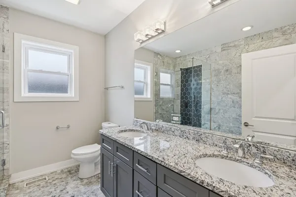 a bathroom with a granite countertop sink mirror vanity and toilet
