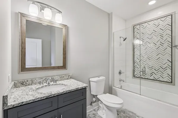 a bathroom with a granite countertop toilet a sink and a mirror