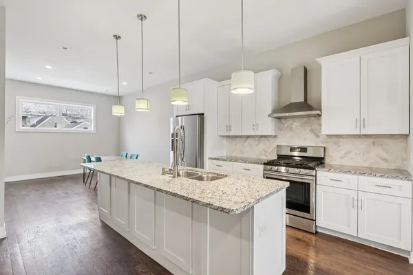 a kitchen with kitchen island a stove a sink a center island and wooden floor